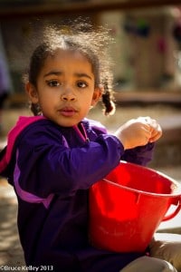 Jeune fille jouant avec un seau rouge dans le cadre d'un programme d'études adapté à l'âge de Denver Waldorf School
